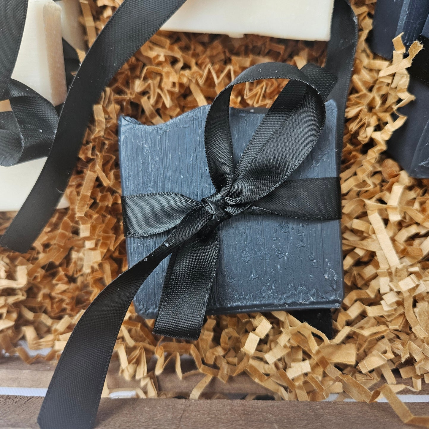 Blue gift box with black ribbon on a bed of brown paper