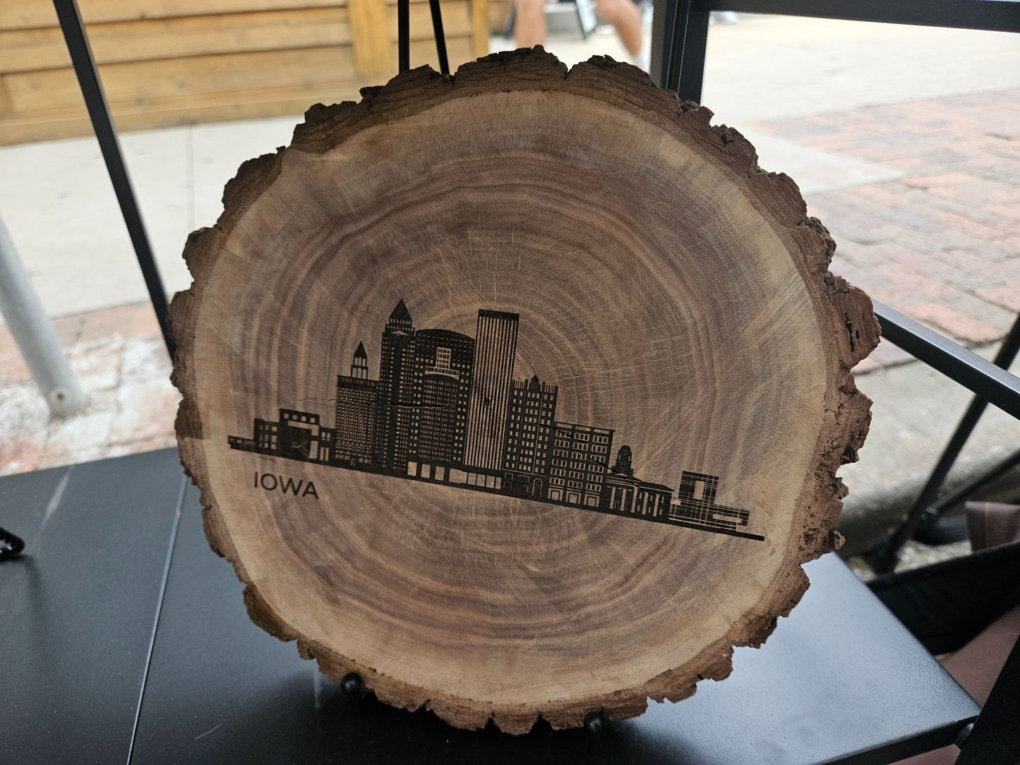 Wooden slice with engraved skyline and 'Iowa' text on a table.