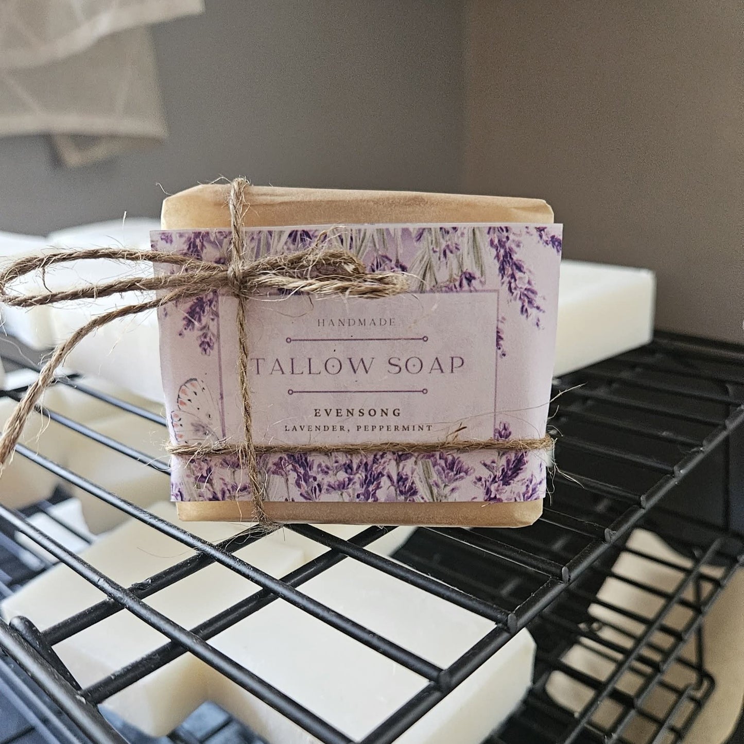 Handmade tallow soap with a decorative label on a black metal rack.