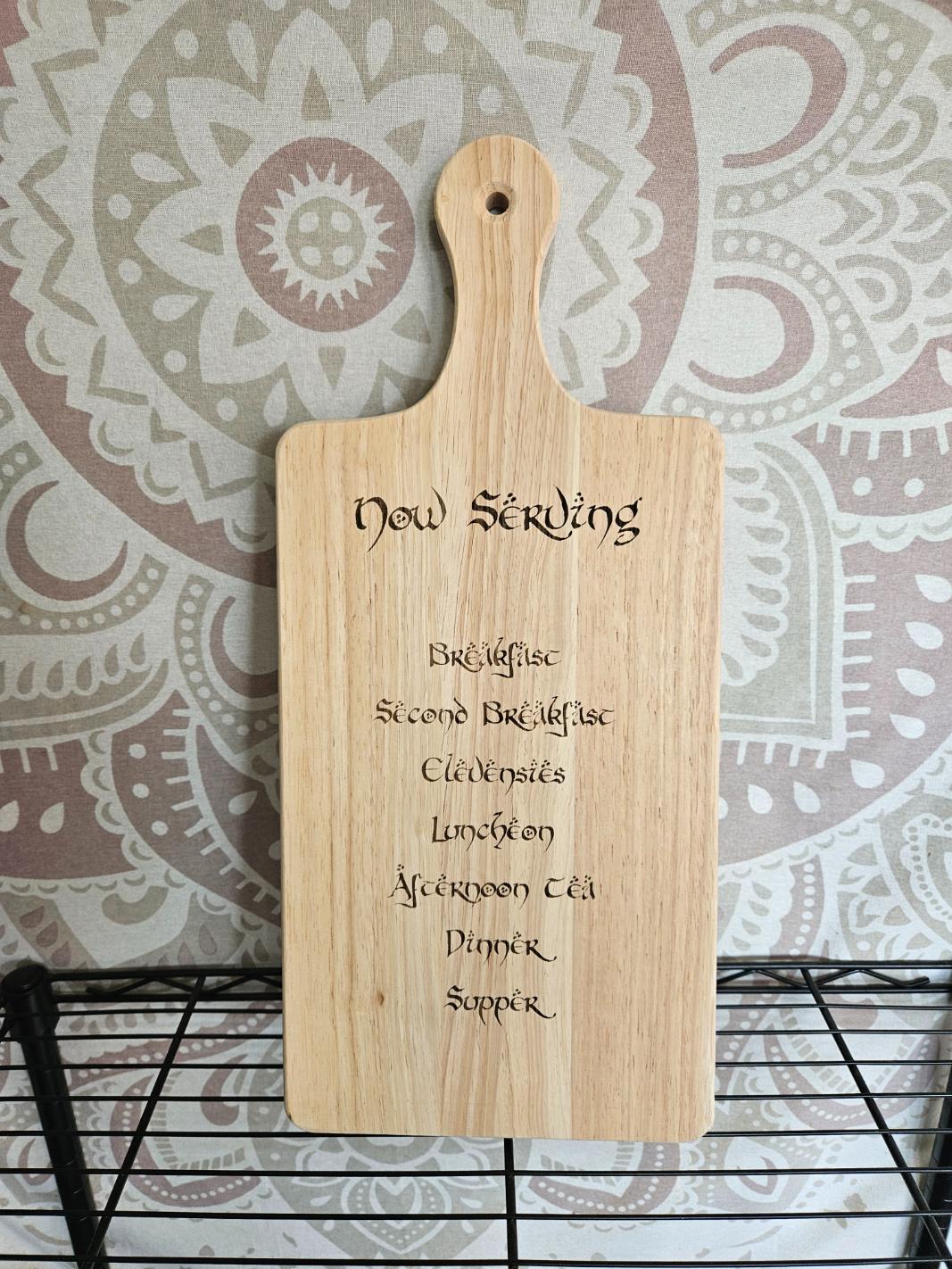 Wooden cutting board with engraved text on a patterned wall background