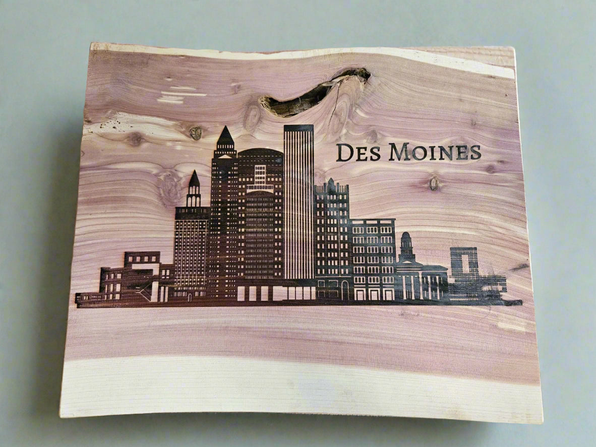 Wooden plaque with engraved skyline of Des Moines on a wooden surface