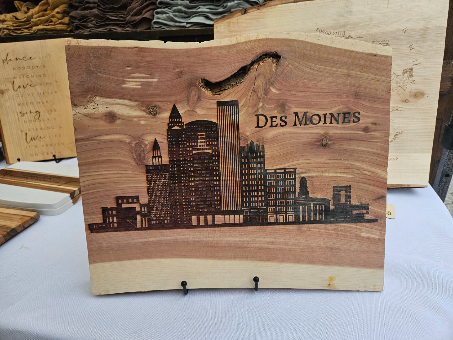 Wooden plaque with engraved cityscape and 'Des Moines' text on a white surface