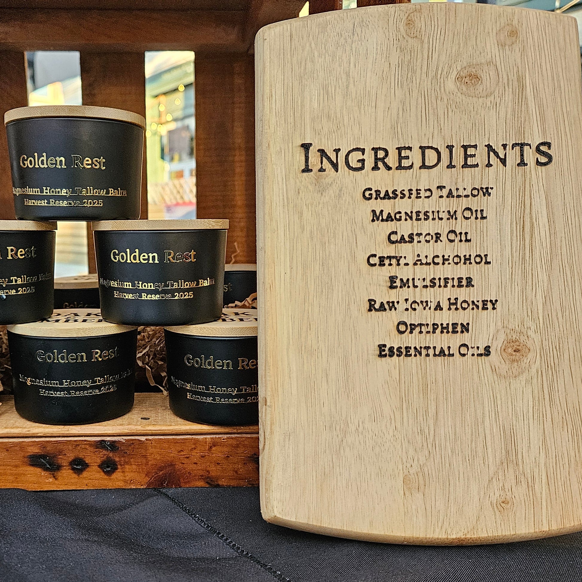 Set of black containers labeled 'Golden Rest' on a wooden stand with a wooden board listing ingredients.