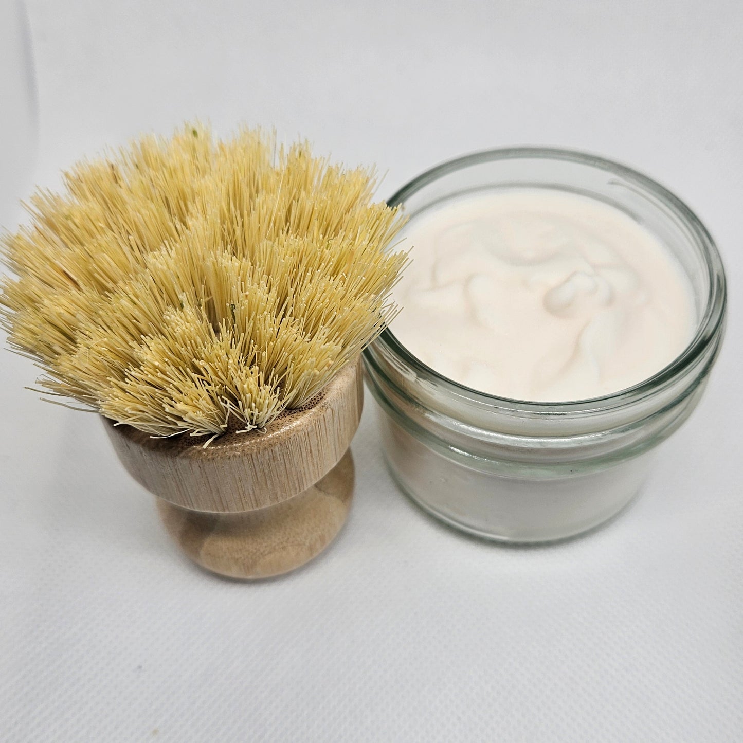 Glass jar with white powder and wooden brush on a white background